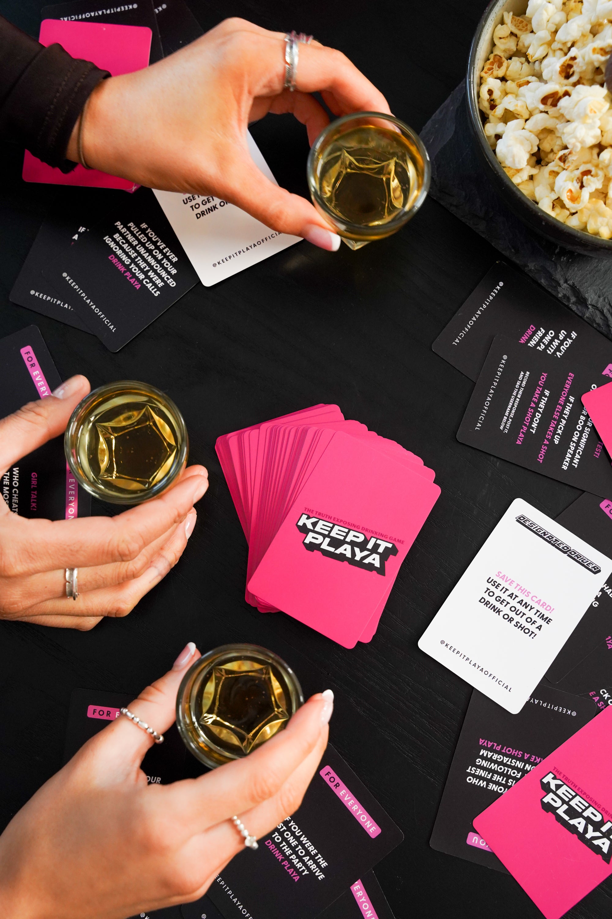 image of hand holding Keep It Playa girls night edition box with cards spread out on table