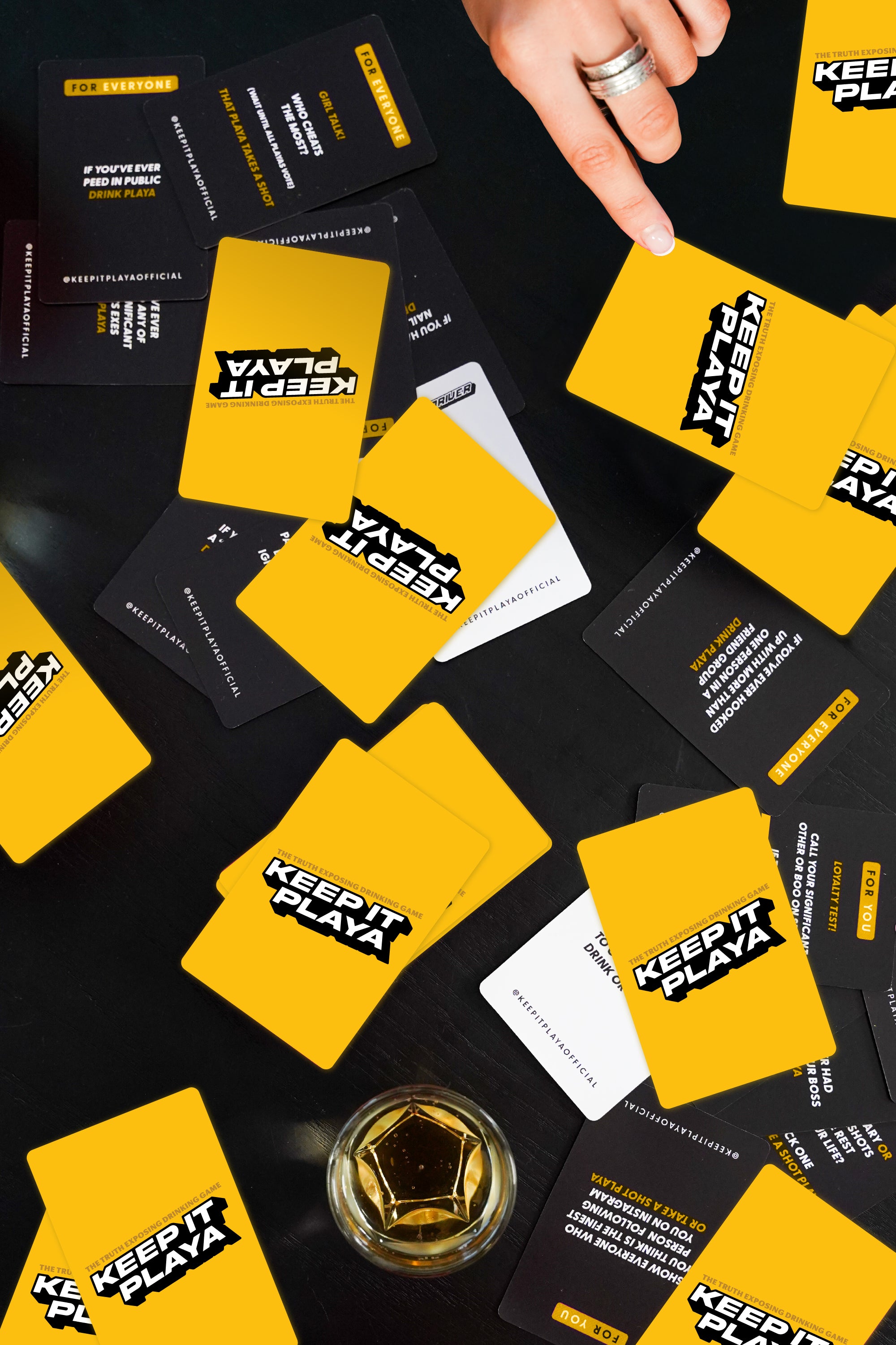 image of hand holding Keep It Playa family night edition box with cards spread out on table