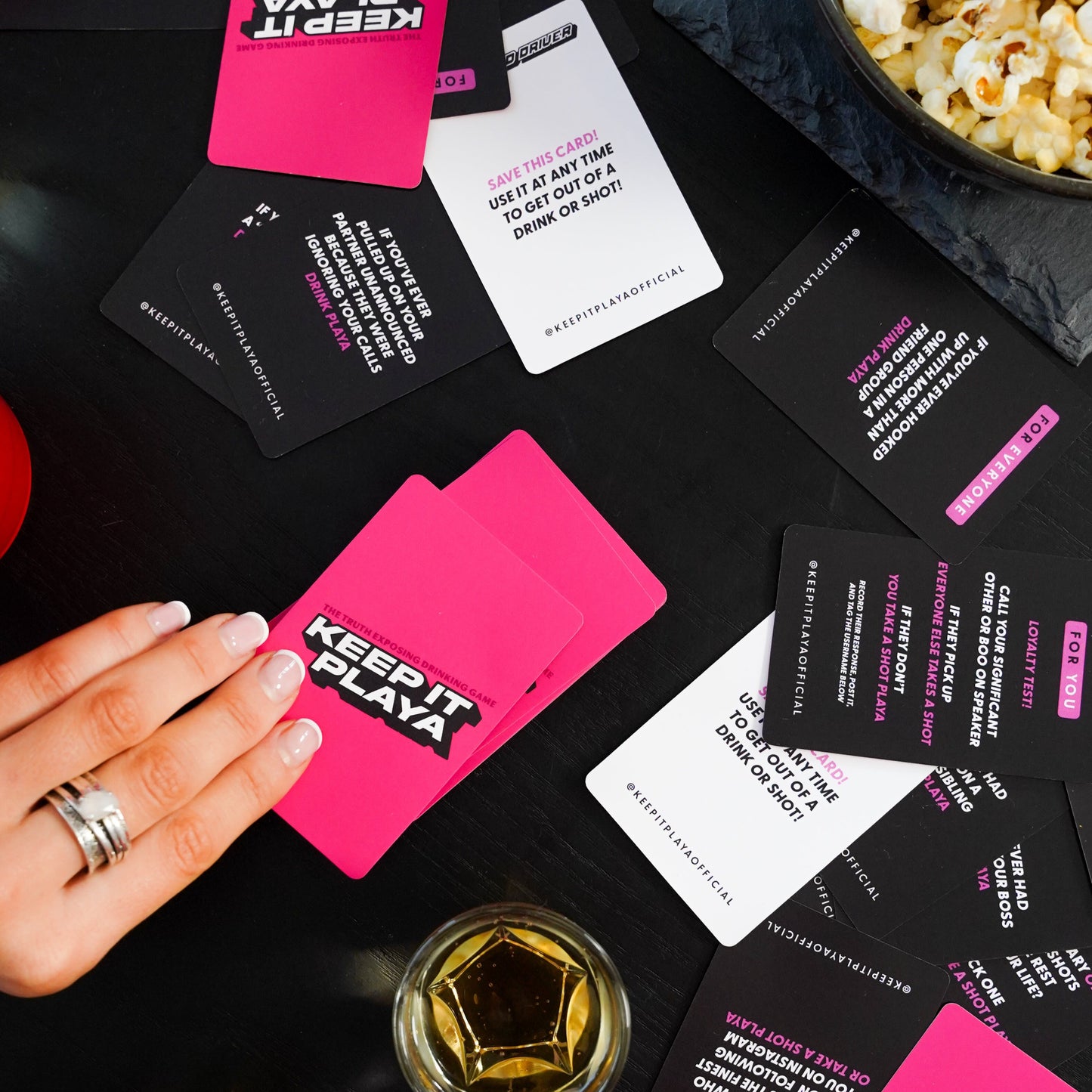 image of Keep It Playa girls night edition front of box being held by a hand with cards spread on table